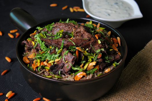 A delicious serving of spiced meat with rice, nuts, and herbs in a bowl.