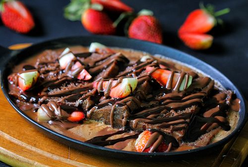 Free Indulge in a rich chocolate brownie dessert drizzled with syrup and fresh strawberries. Stock Photo