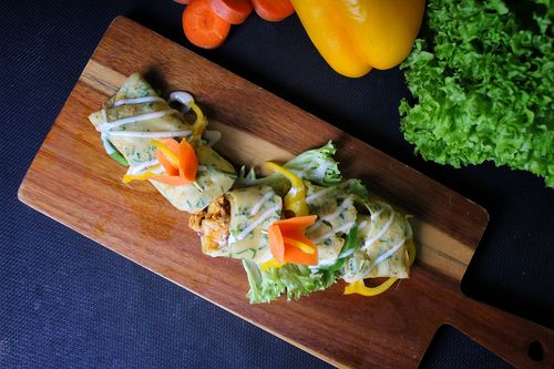 Free A beautifully arranged vegetable wrap on a wooden board with fresh ingredients, highlighting food photography essentials. Stock Photo