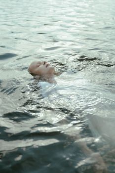 一个女人闭着眼睛漂浮在水面上，这平静的场景营造出一种宁静而沉思的氛围