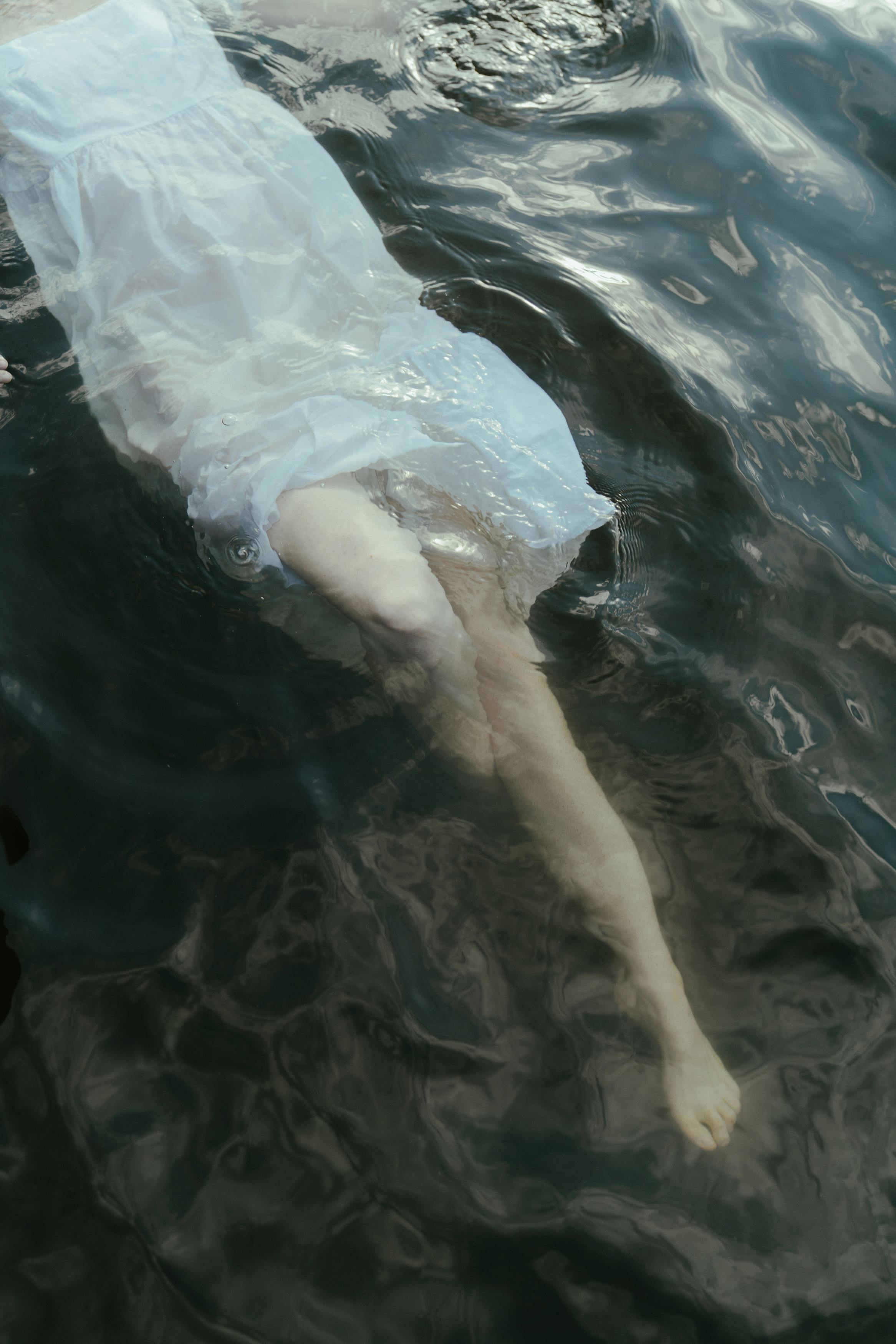 双腿浸入水中的艺术镜头，搭配飘逸的白色连衣裙，传达出宁静的心情