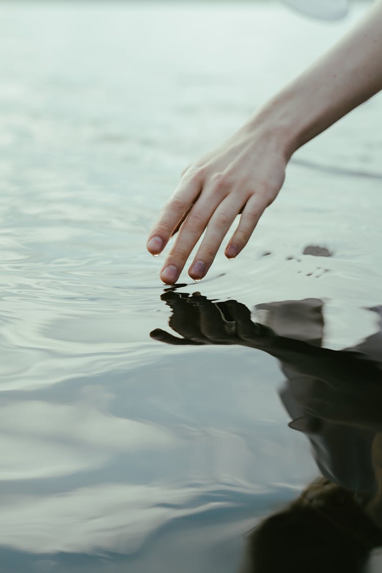 A Person Touching The Water Surface