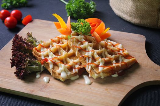 Close-up of waffles with cream and fresh vegetables on a board, perfect for food presentation ideas.