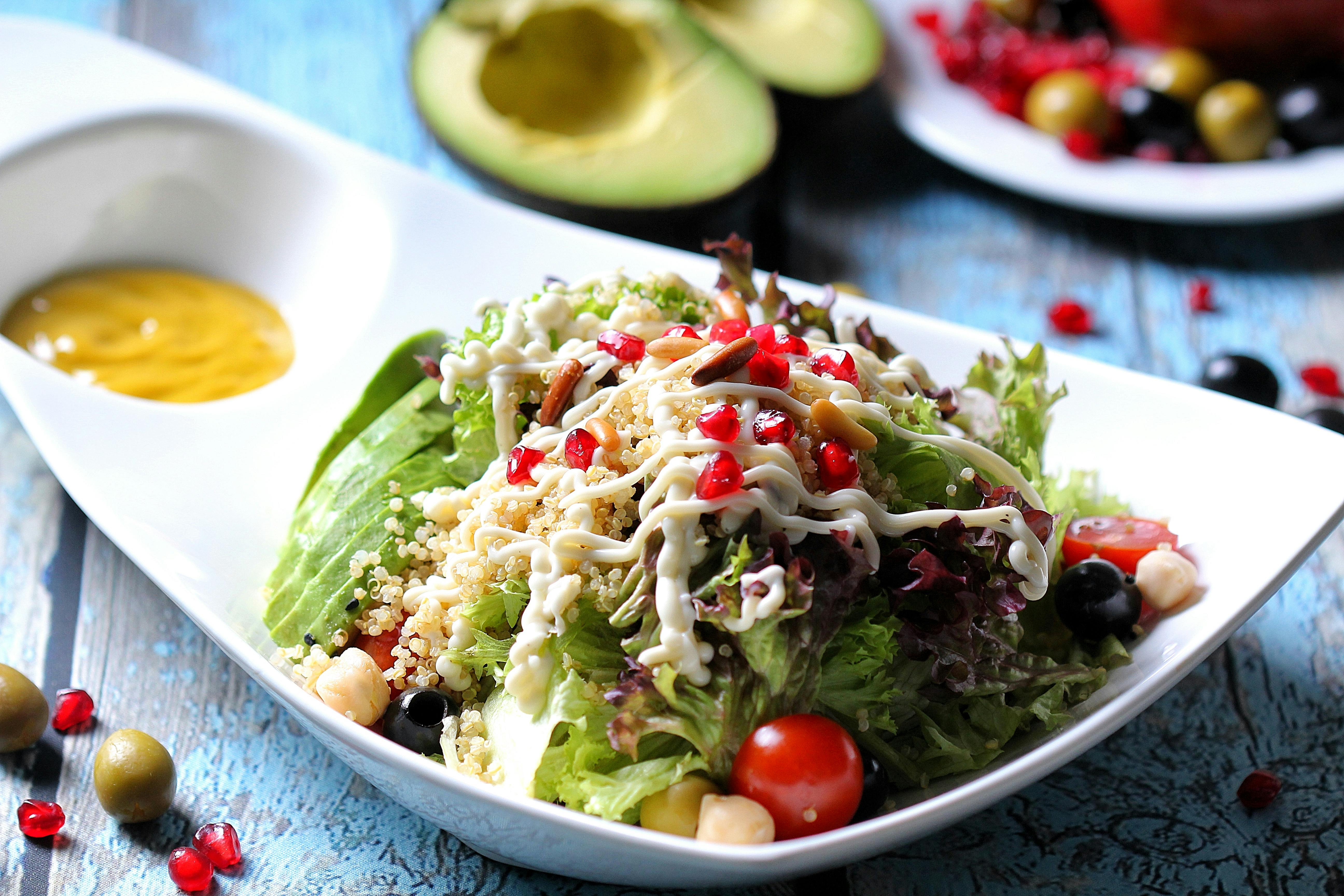 Vibrant quinoa salad with avocado, cherry tomatoes, and creamy dressing on a stylish plate.