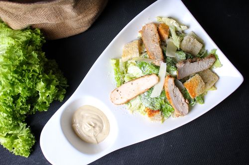 Free Top view of a chicken Caesar salad on a white plate with Caesar dressing. Stock Photo