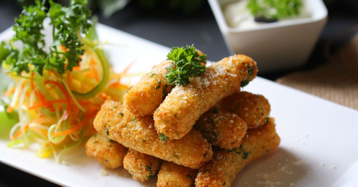 Deliciosos palitos crocantes de mozarela servidos com salada de vegetais frescos e molho cremoso.