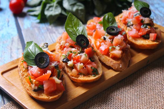 Delicious bruschetta topped with tomatoes, olives, and basil on a wooden tray.