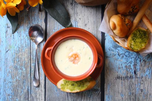 Top view of a delicious creamy shrimp soup with bread on a rustic table.