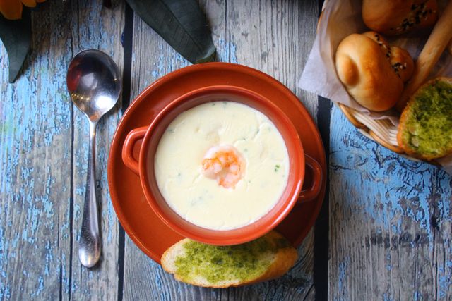 Top view of a creamy shrimp soup in a terracotta bowl with fresh bread, perfect for a cozy meal.