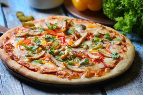 Chicken pizza topped with bell pepper strips, pickled jalapeno slices, melted cheese and cilantro