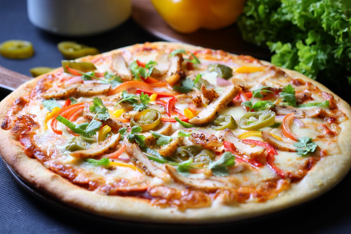 Free Pizza With Green and Red Bell Pepper and Green Leaves on White Ceramic Plate Stock Photo
