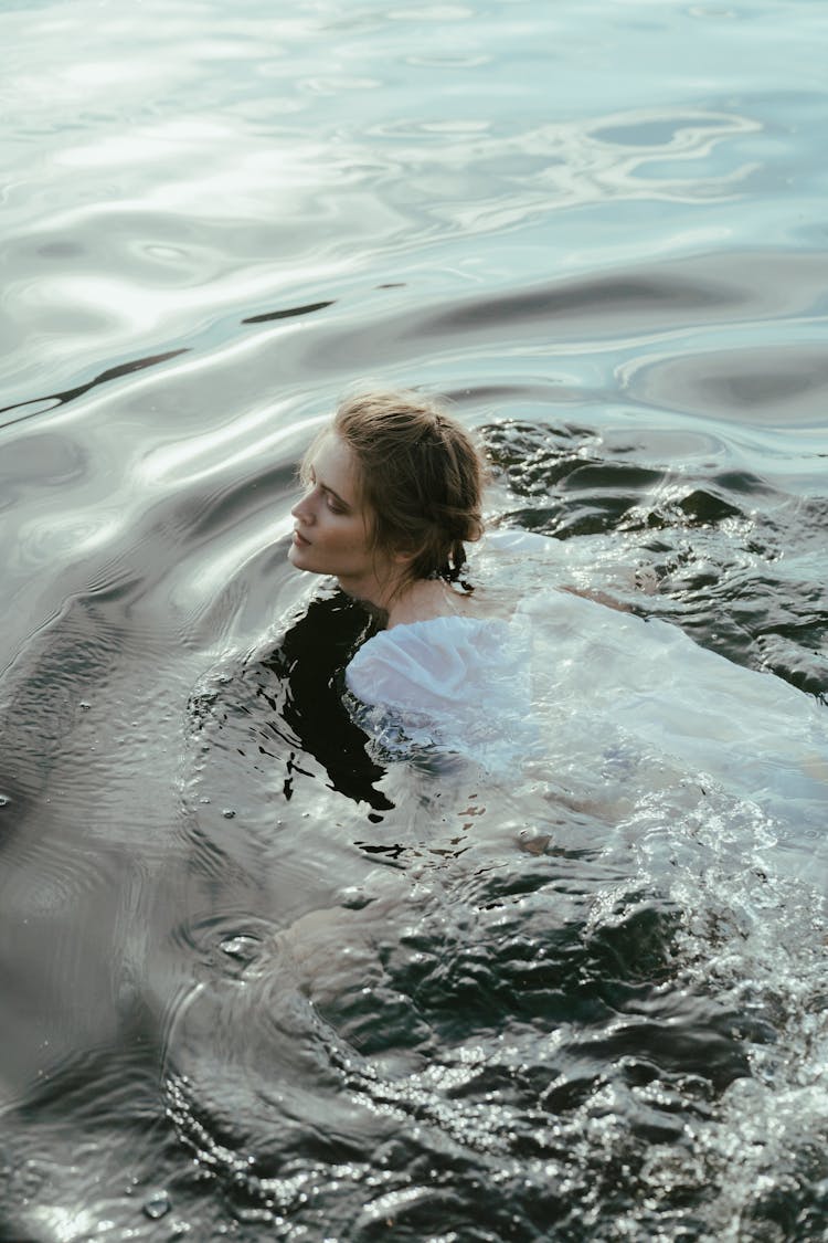 Woman In White Dress Swimming On A Lake