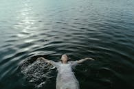 一个女人平静地漂浮在平静的水中，散发着宁静和自由