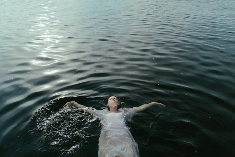 Photograph Of A Woman In A White Dress Floating On Water