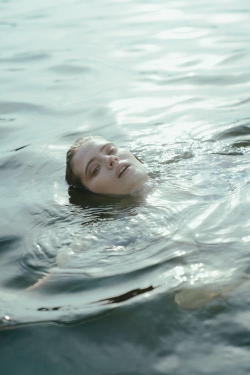 Free A woman peacefully drifting in calm water, evoking a sense of tranquility and freedom. Stock Photo