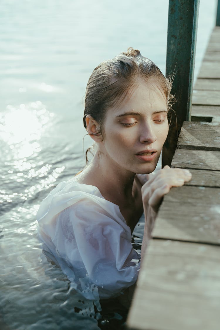 Close-Up Shot Of Drenched Woman Holding On Wooden Planks