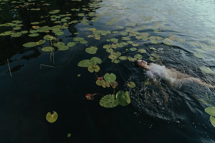 Photo Of A Woman Floating Near Lily Pads