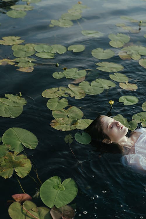 Woman Floating on Water with Water Lilies
