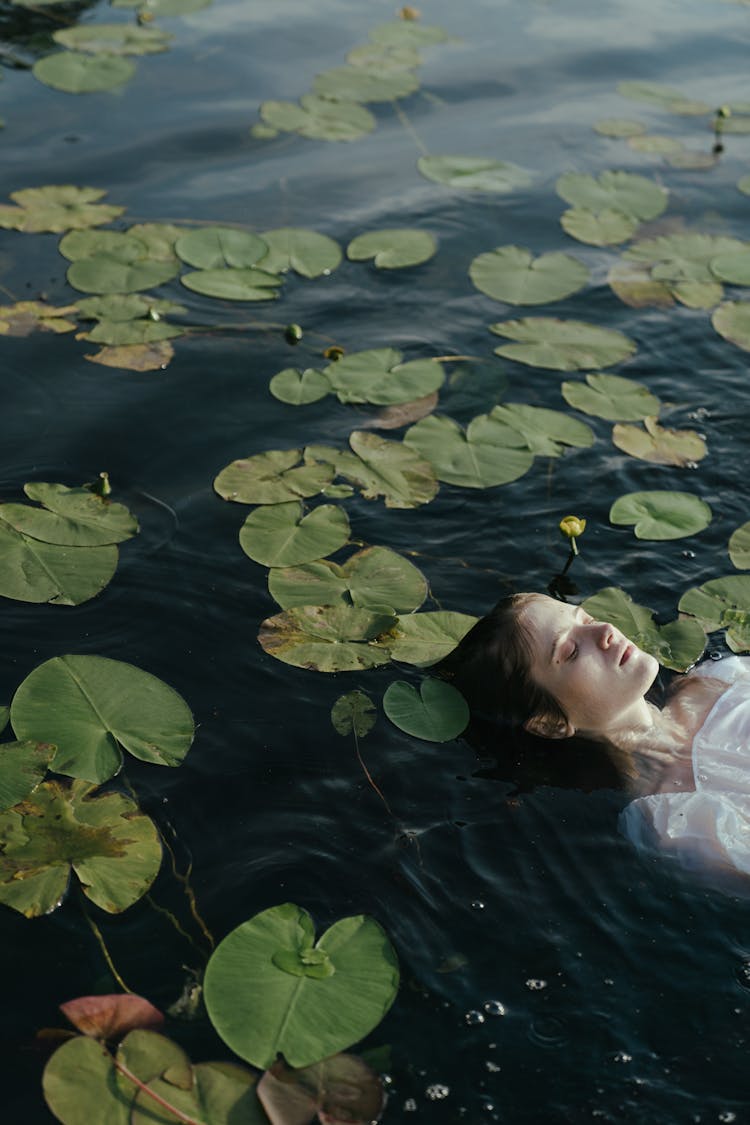 Woman Floating On Water With Water Lilies