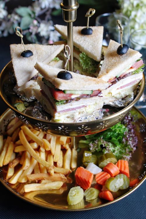 Free Delicious sandwiches, fries, and pickles elegantly presented on a tiered platter. Stock Photo