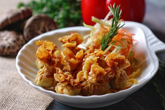 Delicious crispy fried dumplings served with fresh carrot and cucumber garnish, perfect for a gourmet meal.