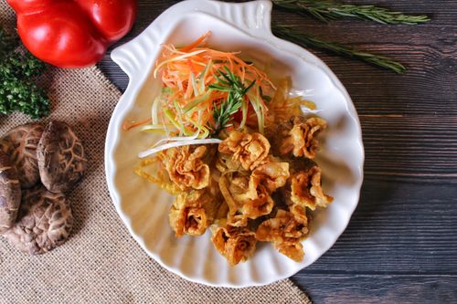 Free Appetizing fried dimsum with garnish served on a ceramic plate, top view. Stock Photo