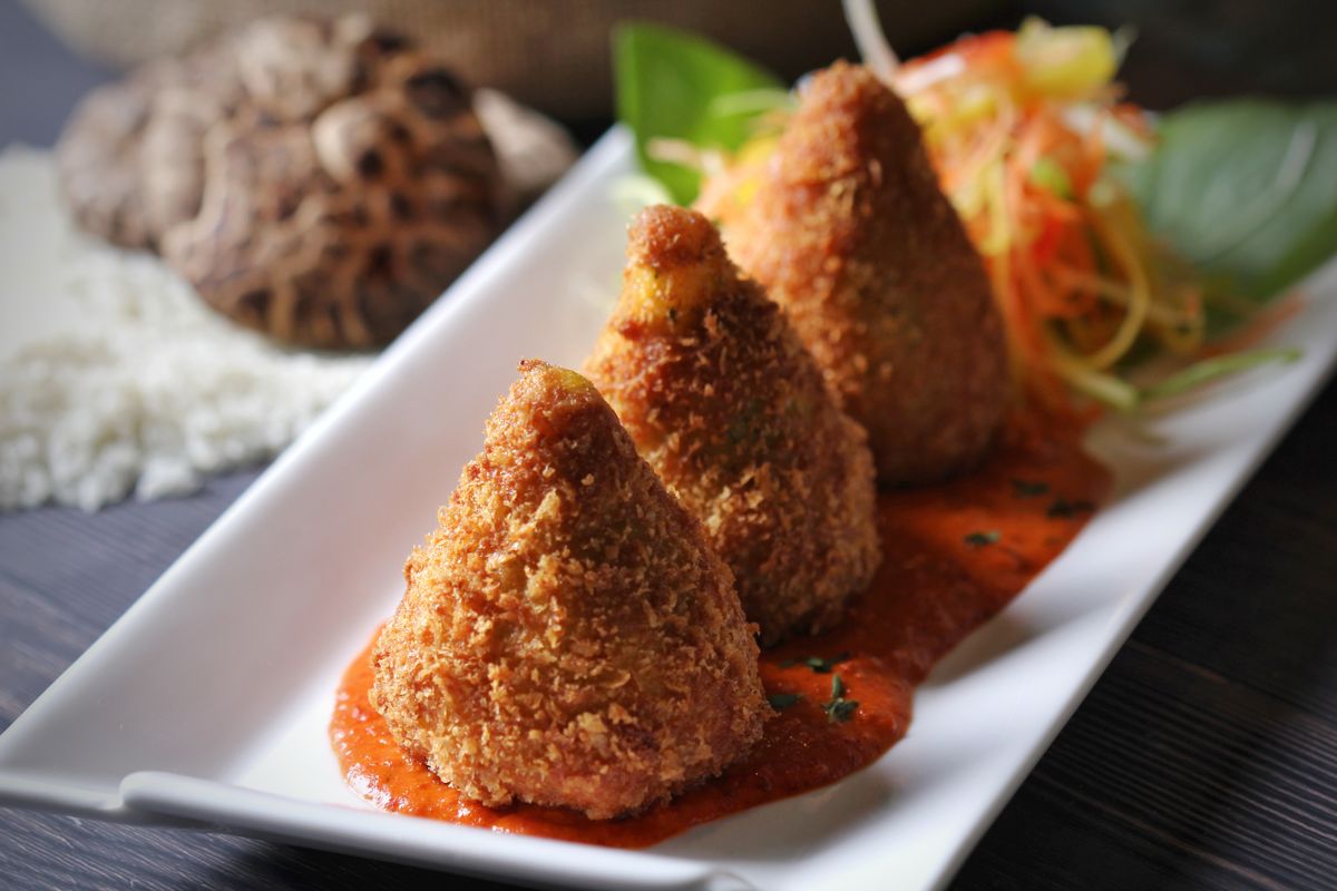 Fried appetizer bites on a white plate with a spicy dipping sauce