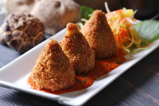 Close-up of crispy fried appetizers with fresh garnish on a white plate, highlighting texture.