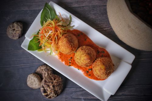 Free Italian arancini served with tomato sauce and fresh vegetables in a top view presentation. Stock Photo