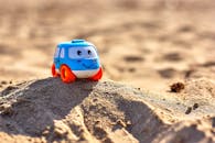 Blue and White Toy Car on Beach Sand