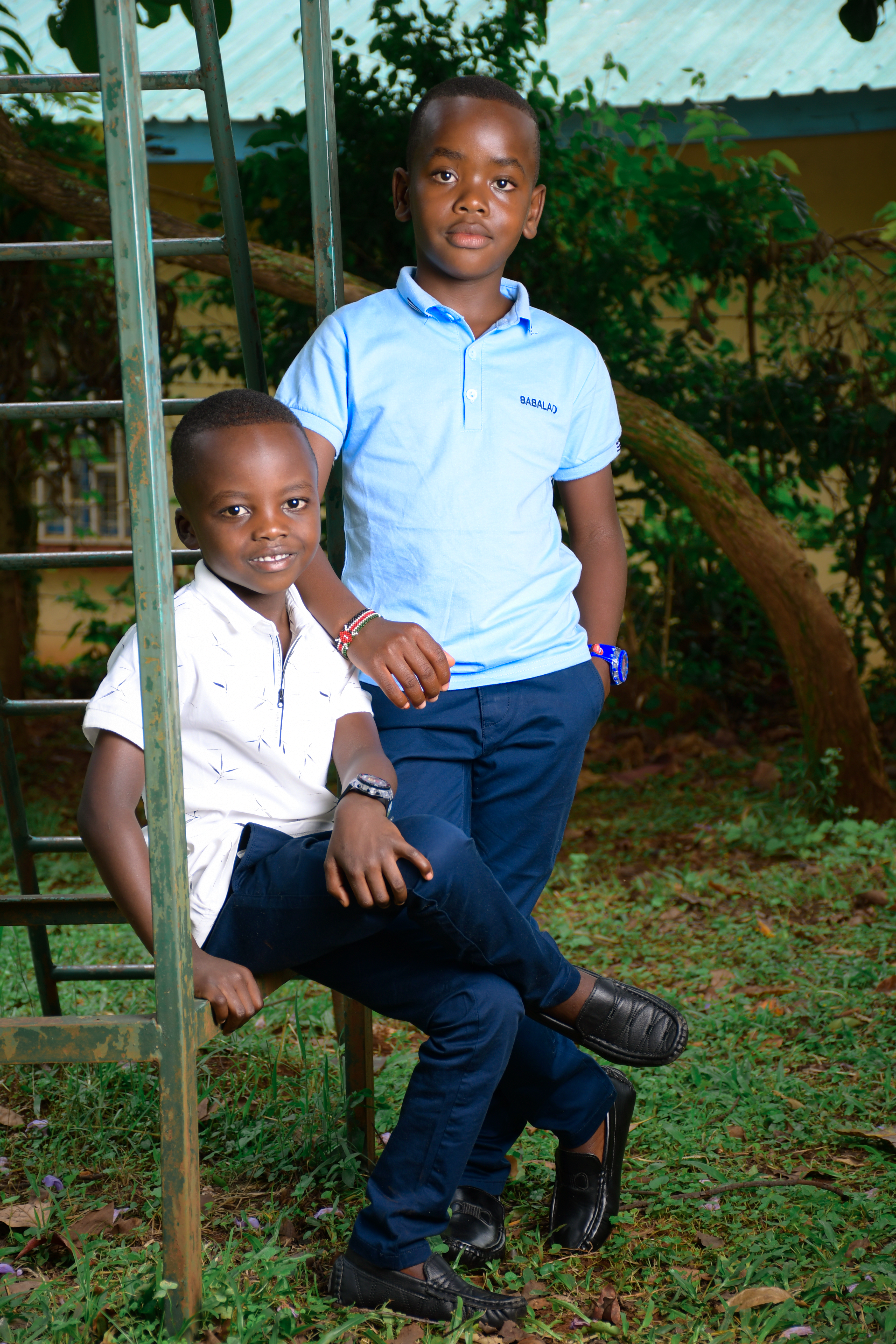 Two young brothers pose in an outdoor setting, displaying joyful expressions and casual style.
