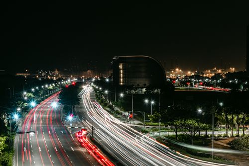 Free Long exposure of Singapore city street with vibrant light trails and urban skyline at night. Stock Photo