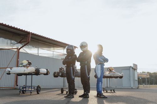 Free Three go-kart racers in helmets posing with their karts during sunset, showcasing motorsport spirit. Stock Photo