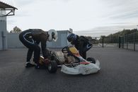 两名赛车手在赛道上检查卡丁车，为即将到来的比赛做准备，这体现了运动精神和对精确性的追求