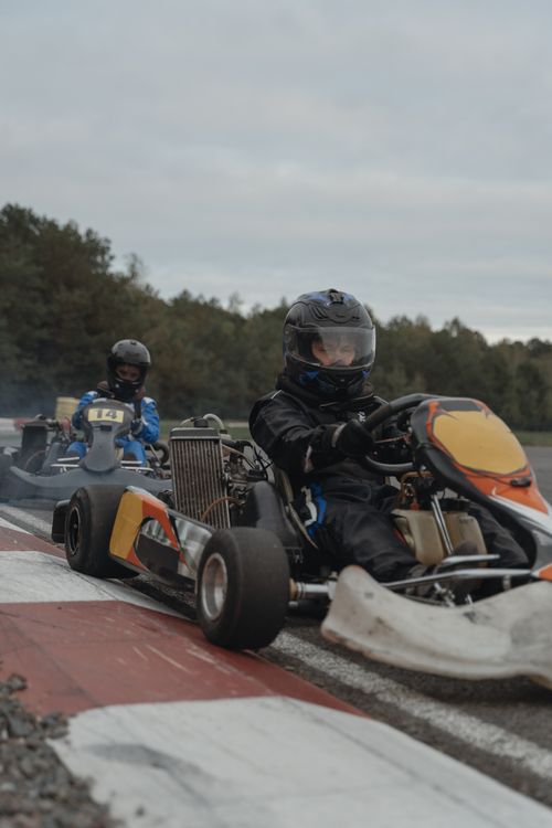Free Kart racers competing on an outdoor track wearing helmets and suits. Stock Photo