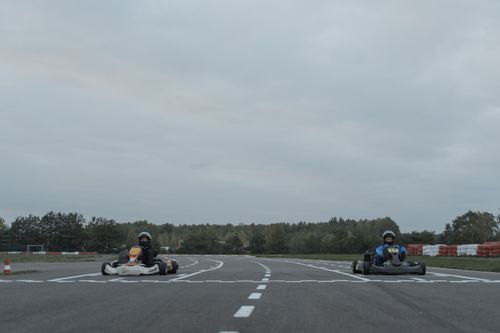 Free Two athletes racing go-karts on an outdoor racetrack in overcast conditions. Stock Photo