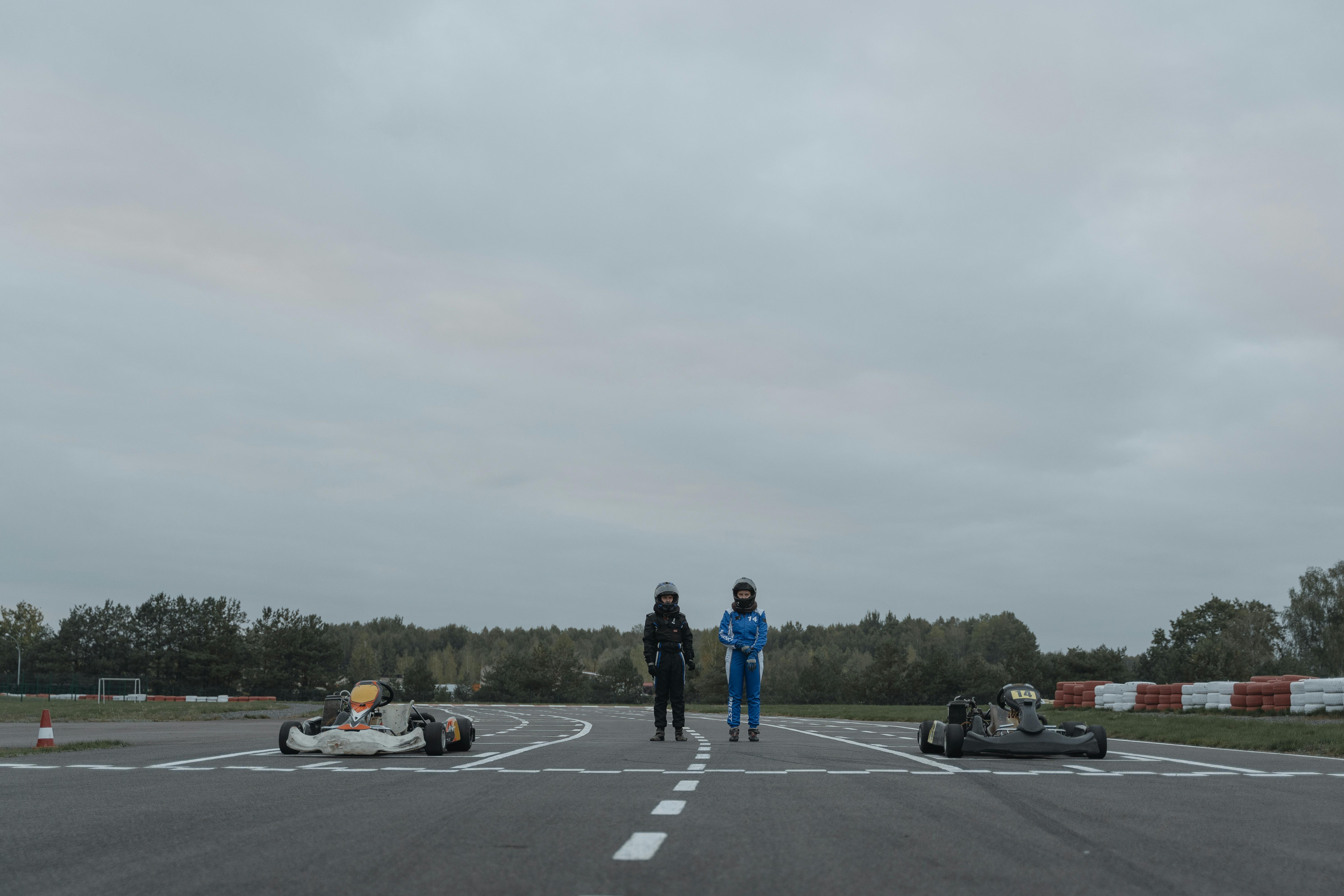 two go kart drivers standing in racetrack