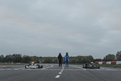 Two Go-Kart Drivers Standing in Racetrack
