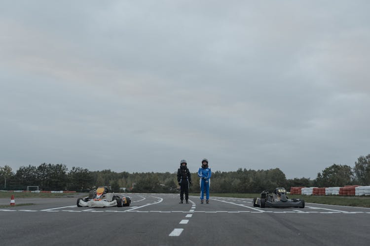 Two Go-Kart Drivers Standing In Racetrack