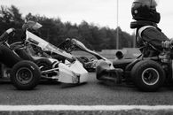 Black and white image of go-kart racers in action on the track, emphasizing speed and competition.
