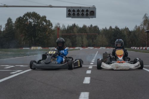 Free Two go-karts competing fiercely on an outdoor racing track surrounded by trees. Stock Photo