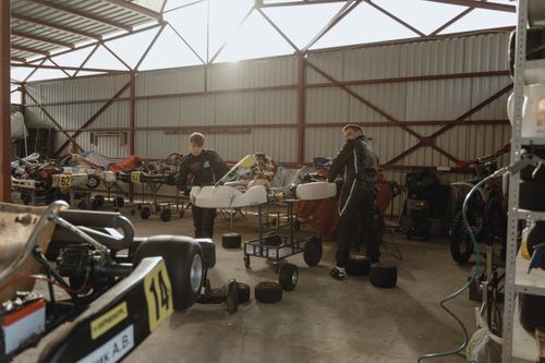 Free Two mechanics working on go-karts in an indoor workshop with natural lighting. Stock Photo