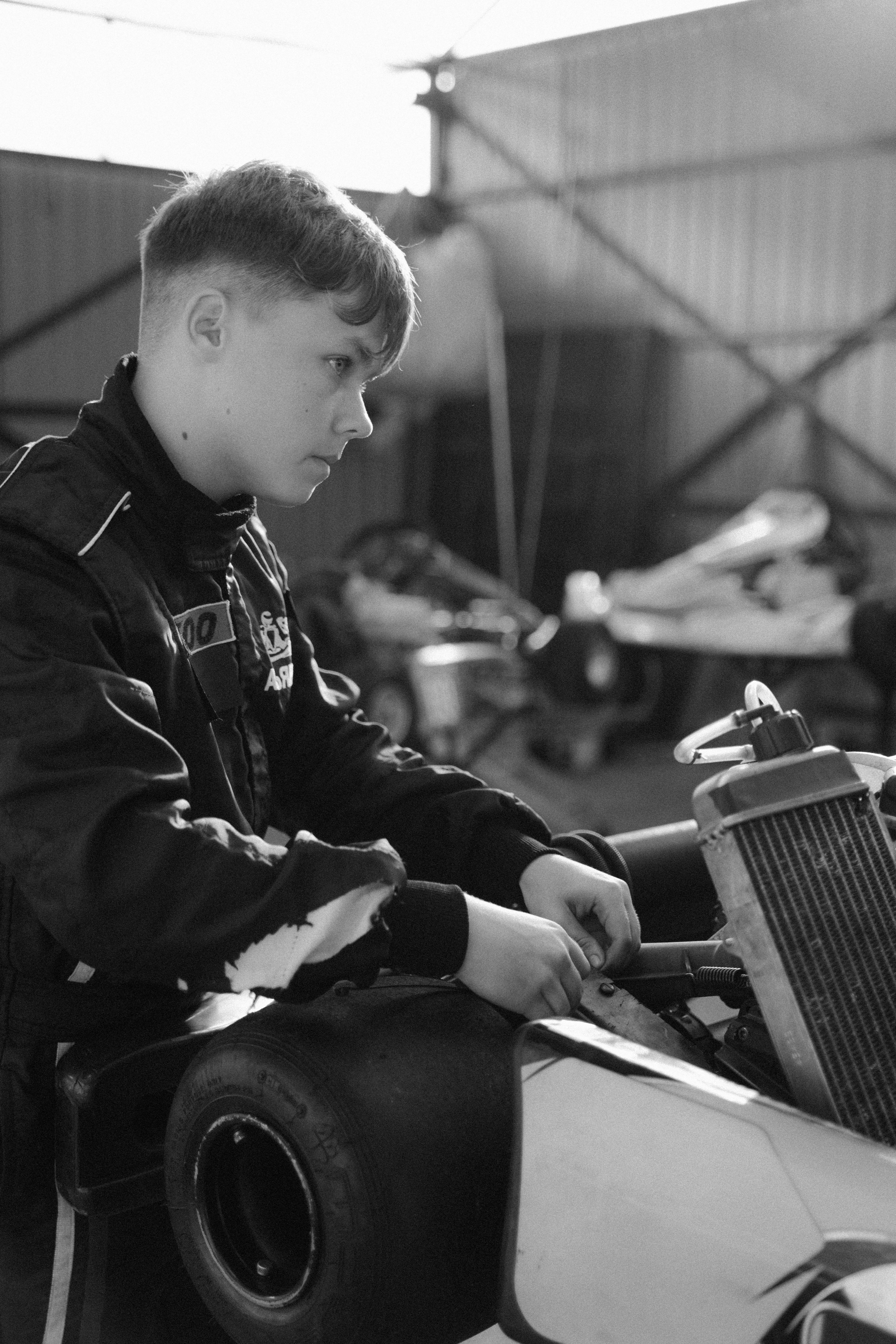 grayscale photo of a man fixing the go kart