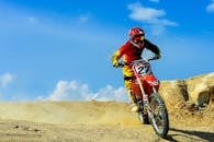 在蓝天下，越野摩托车赛车手飞驰穿过尘土飞扬的赛道，这是一项人数众多的户外运动