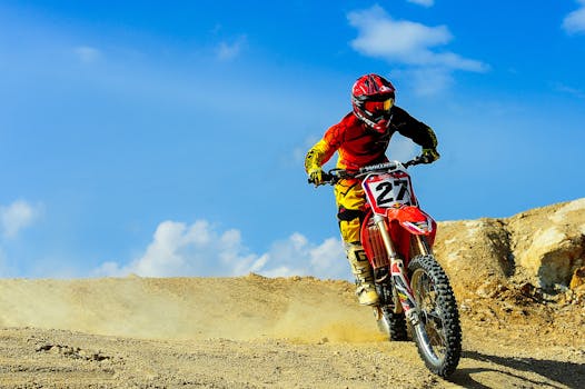 Motocross racer speeding through a dusty track under blue skies. Action-packed outdoor sport.