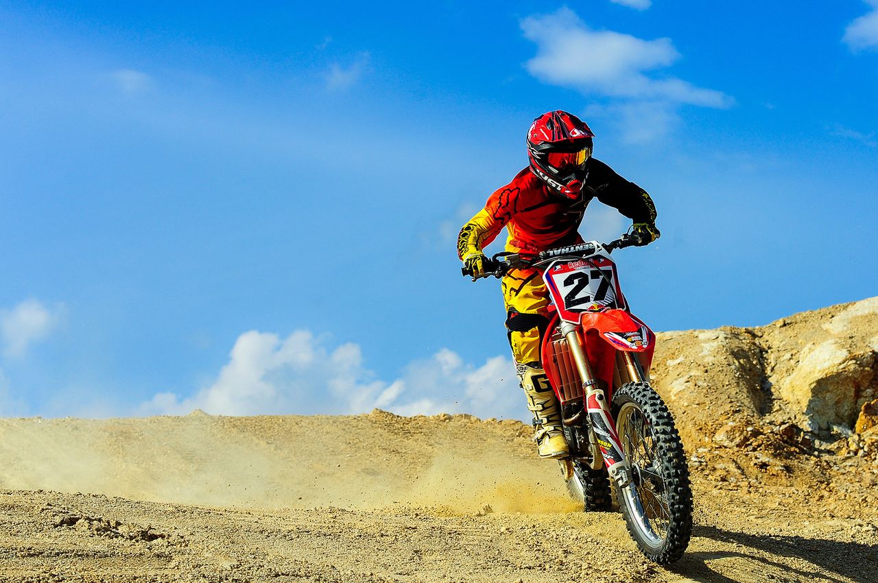 motocross racer speeding through a dusty track under blue skies action
