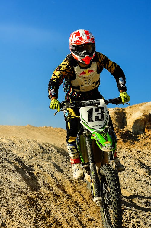 Free Man Riding Motocross Dirt Bike on Hill Stock Photo