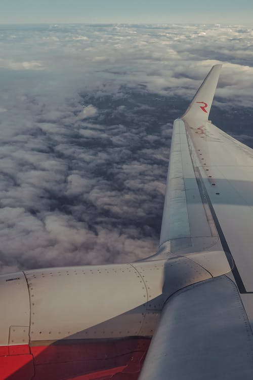 White Airplane Wing Above Cumulus Clouds