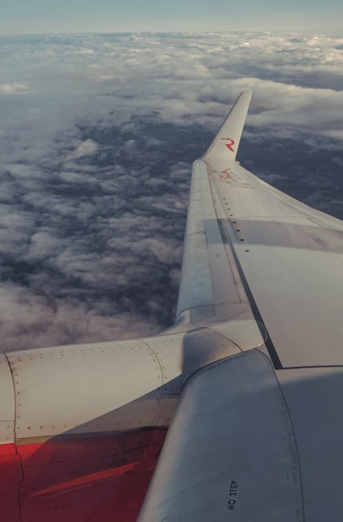 White Airplane Wing Above Cumulus Clouds