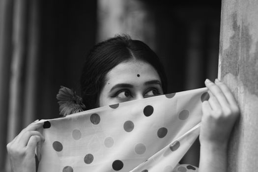 Ethnic  woman with bindi hiding behind scarf